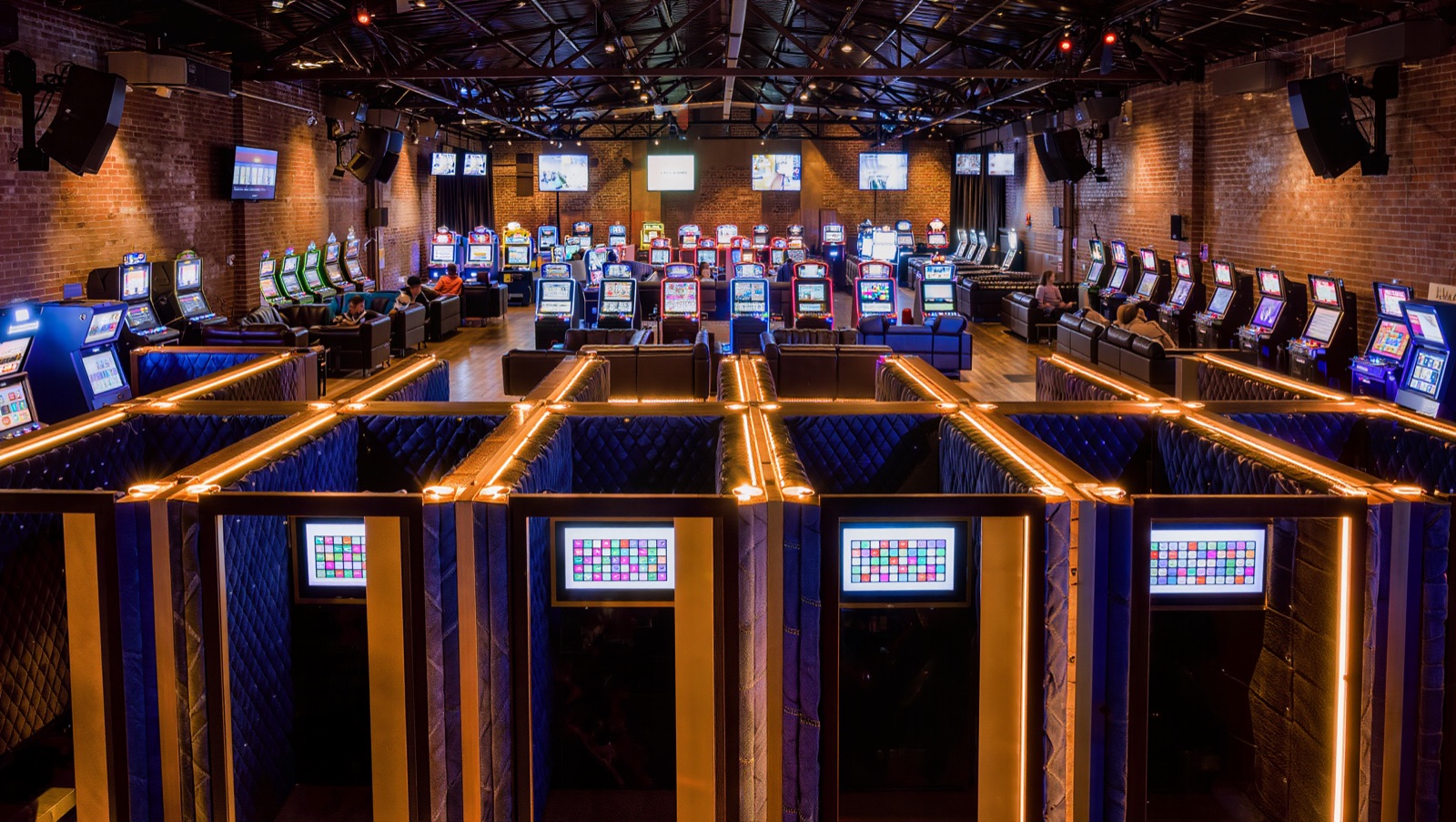 Concept render — independent mode: denim-clad sound booths glowing amber, each picking its own channel, every screen in the hall playing something different