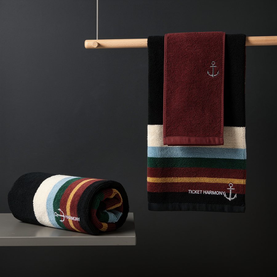 Harmony towel on a rail — striped color blocks in the house palette with anchor wordmark